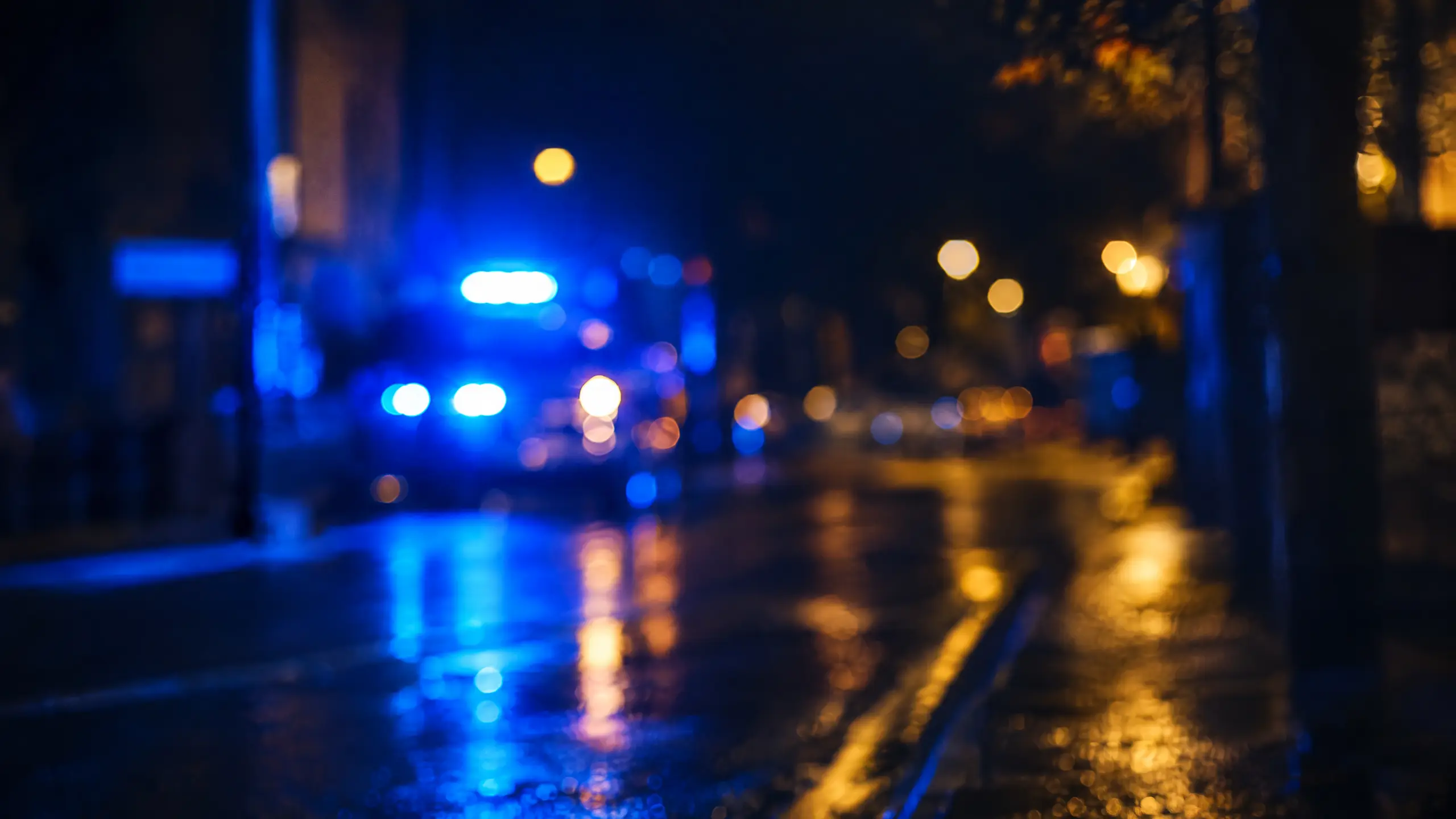 Blurred blue police lights on a dark, wet city street