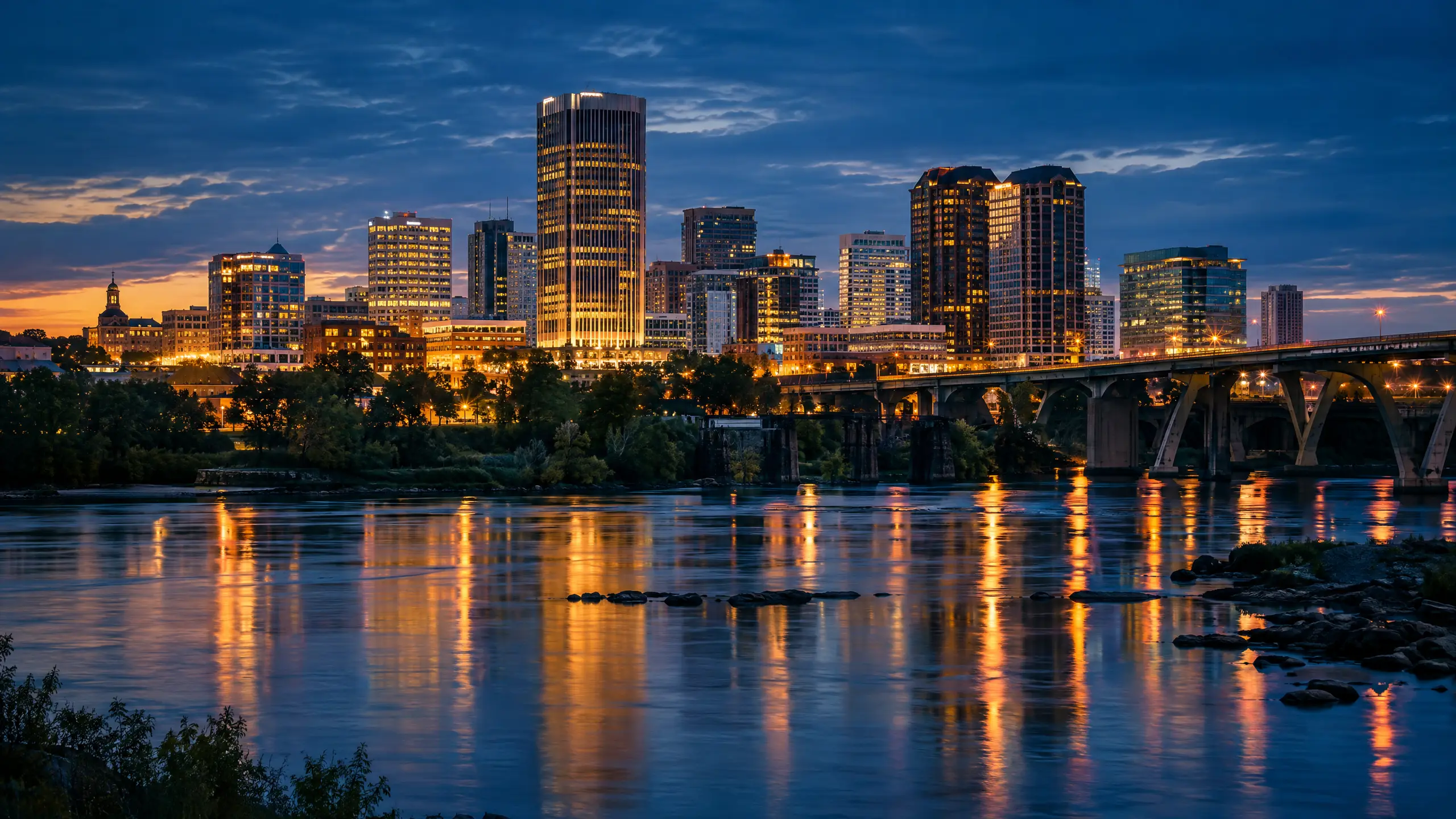 Richmond, Virginia skyline across the James River at blue hour with city lights reflecting on the water